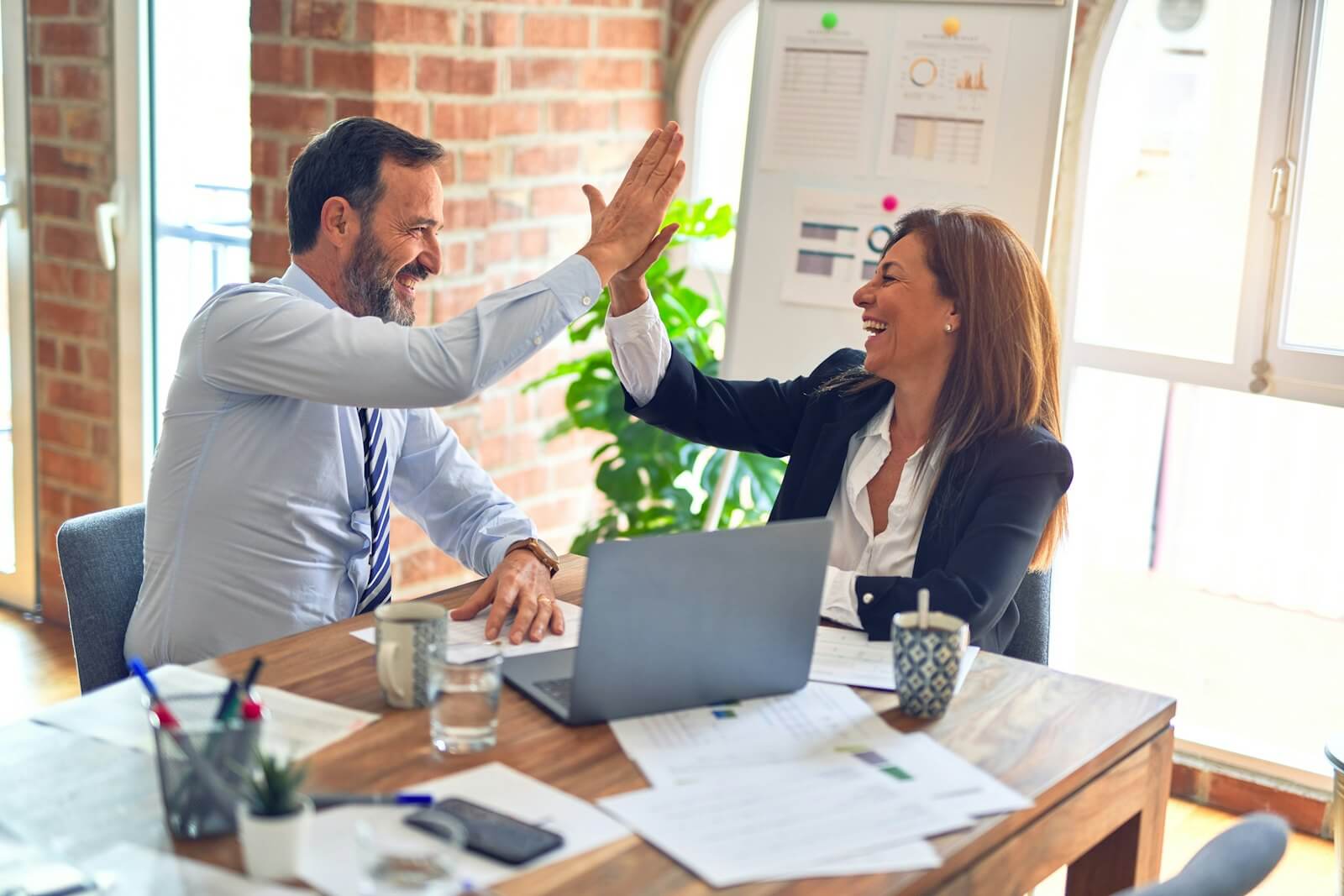 Two business owners celebrating results at their laptop